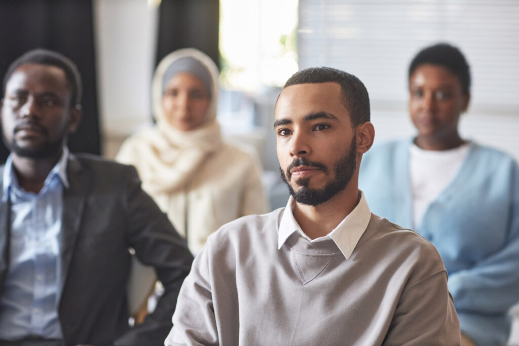 Serious multiethnic male immigrant listening to speaker